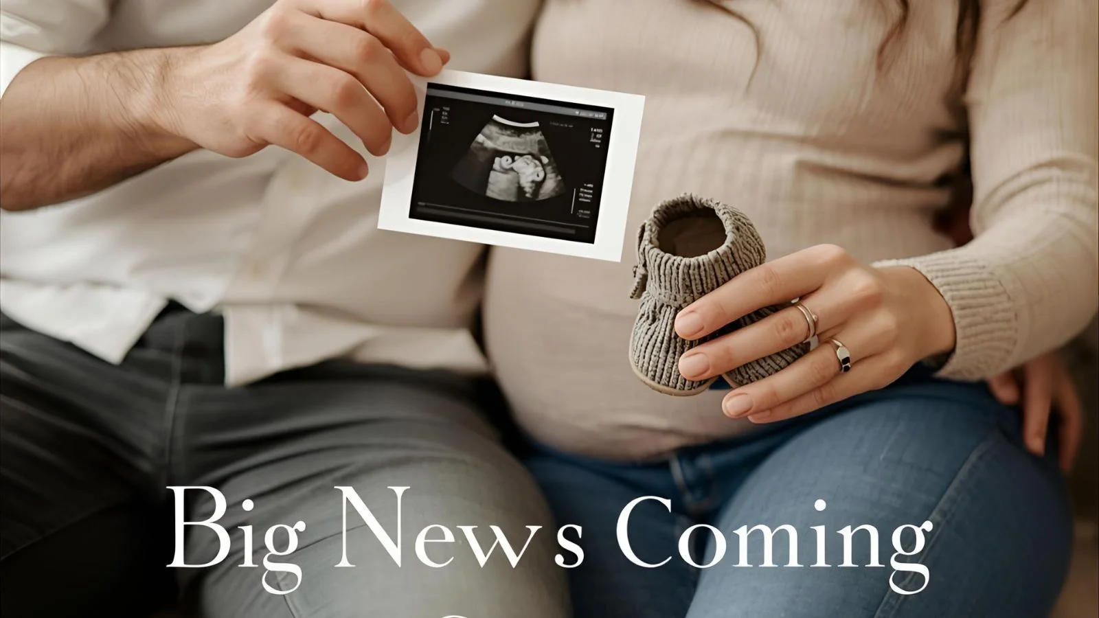 Expecting couple smiling on a couch while holding an ultrasound photo and baby shoes.
